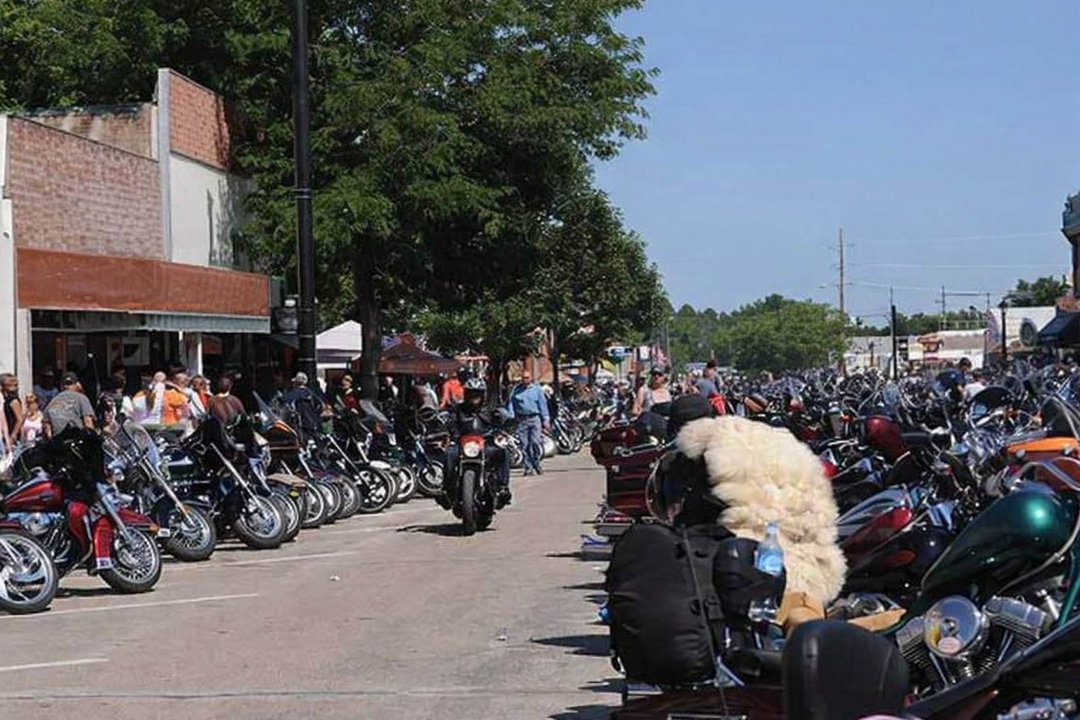 Gata fylld med parkerade motorcyklar och cyklister i en stadsmilj%C3%B6.