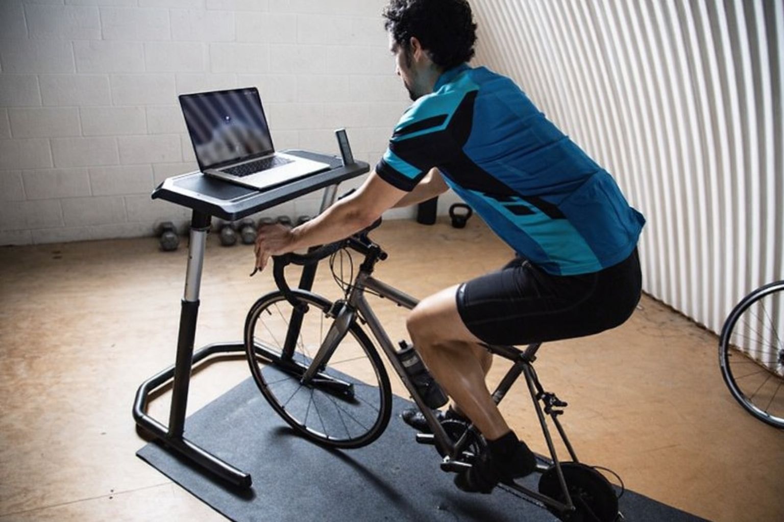 Cyklist med laptop på ställning, tränar inomhus